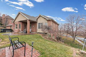 Rear view of property featuring a patio area, brick siding, and a hot tub