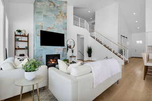 Living area featuring wood finished floors, a high ceiling, a high end fireplace, a barn door, and recessed lighting