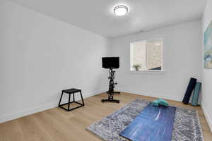 Exercise area with light wood-style floors and a textured ceiling