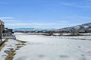 Yard covered in snow featuring a mountain view