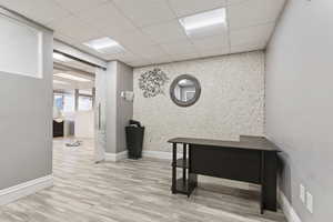 Office with an accent wall, light wood-style floors, and a paneled ceiling