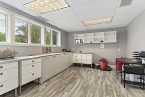 Kitchen featuring white cabinets, a drop ceiling, light wood finished floors, and light countertops