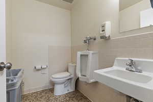 Bathroom with tile walls, tile patterned flooring, and a wainscoted wall