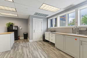 Laundry room featuring light wood-style floors and a drop ceiling