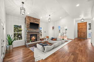 Living room featuring lofted ceiling, hardwood / wood-style floors, a fireplace, and recessed lighting