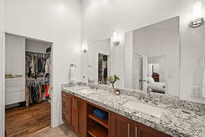 Bathroom featuring double vanity, a walk in closet, ensuite bathroom, and a high ceiling