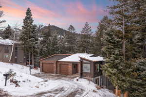 View of front of house featuring stone siding, a tiled roof, and a garage