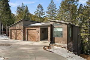 View of front of property featuring concrete driveway, a garage, and stone siding