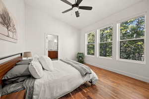 Bedroom featuring lofted ceiling, connected bathroom, wood finished floors, and ceiling fan