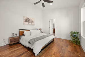 Bedroom with dark wood-type flooring, ceiling fan, and a high ceiling
