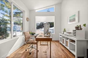 Office space with lofted ceiling and light wood-type flooring