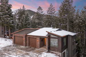View of front facade with a garage, stone siding, and stucco siding