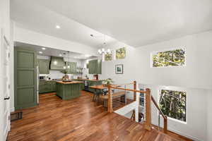 Dining space with dark wood finished floors, hanging lights, plenty of natural light, and a high ceiling