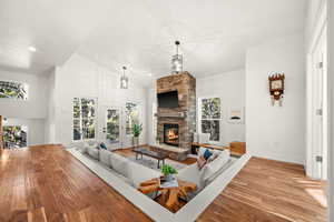 Living area featuring a stone fireplace, hardwood / wood-style flooring, a high ceiling, and recessed lighting
