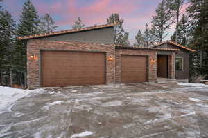 View of front of house with stone siding, a garage, and driveway