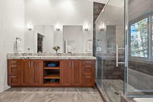 Full bath with double vanity, a shower stall, and a walk in closet