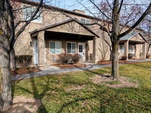 View of front of house with stucco siding, a front lawn, covered porch, and a chimney