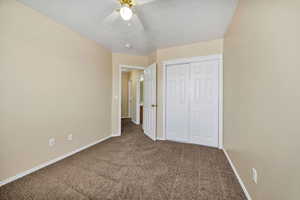 Unfurnished bedroom featuring carpet, a closet, and a ceiling fan