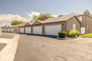 View of front of property featuring community garages, stucco siding, and a shingled roof
