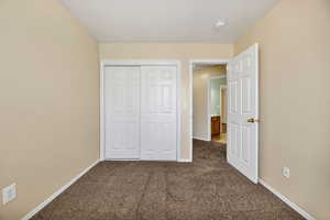 Unfurnished bedroom featuring dark carpet and a closet