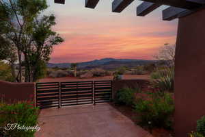 Patio terrace at dusk featuring a gate and a mountain view