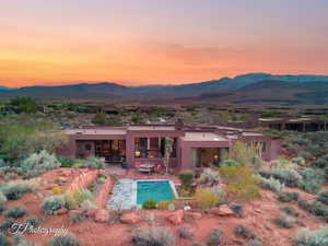 Back of house at dusk featuring a chimney, stucco siding, and a mountain view