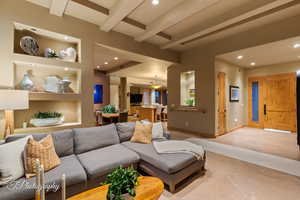 Living room with beam ceiling, recessed lighting, tile patterned flooring, and built in shelves
