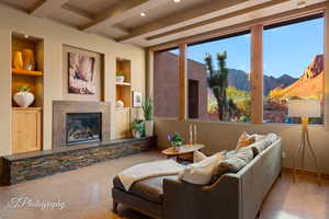 Tiled living room with built in shelves, a mountain view, beam ceiling, a glass covered fireplace, and recessed lighting