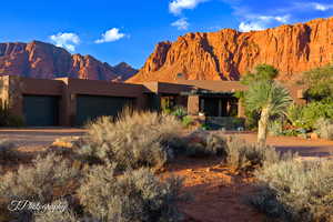 View of front of property with dirt driveway, stucco siding, a mountain view, and a garage