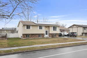 Bi-level home featuring roof mounted solar panels, brick siding, driveway, and an attached carport