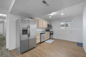 Kitchen with light wood finish cabinetry, stainless steel appliances, light countertops, light wood-style floors, and recessed lighting