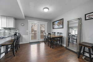 Dining area with a textured ceiling, dark wood finished floors, and plenty of natural light