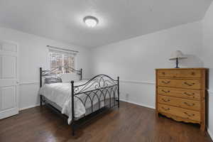 Bedroom with dark wood-style floors and a textured ceiling