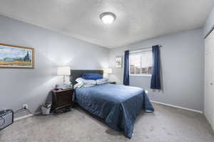 Carpeted bedroom with a textured ceiling and a closet