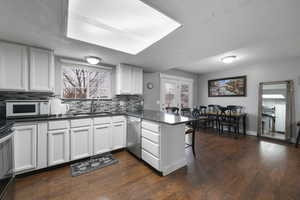 Kitchen featuring a peninsula, white cabinetry, decorative backsplash, and a textured ceiling