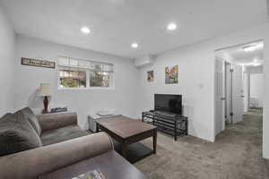 Living area with light carpet and recessed lighting