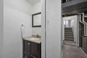 Half bath with vanity, unfinished concrete floors, and heating unit