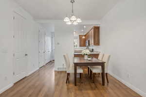 Dining space featuring hanging lights, dark wood finished floors, and ornamental molding