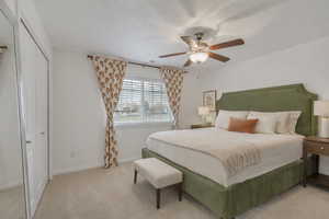 Bedroom with light colored carpet, a ceiling fan, a closet, and a textured ceiling