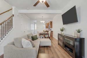 Living room featuring wood finished floors, ceiling fan, ornamental molding, and suspended lighting