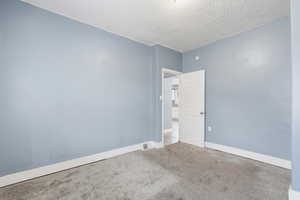 Unfurnished room with a textured ceiling and carpet