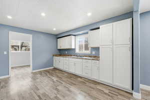 Kitchen with white cabinets, light wood-style floors, and recessed lighting