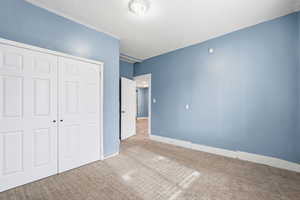 Unfurnished bedroom featuring a closet, carpet, and a textured ceiling