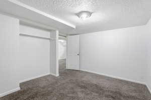 Unfurnished bedroom featuring a textured ceiling, carpet, and a textured wall