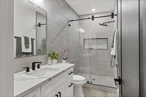 Full bath with vanity, a shower stall, tile walls, and tasteful backsplash