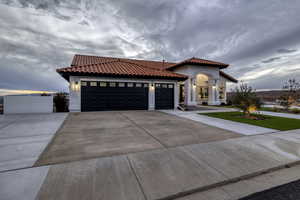 Mediterranean / spanish-style house featuring a tiled roof, concrete driveway, an attached garage, and stucco siding