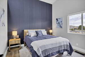 Bedroom with an accent wall and wood finished floors