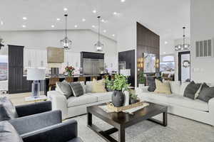 Living area with hanging lights, lofted ceiling, and light wood finished floors