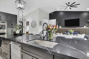 Kitchen with open floor plan, dark stone countertops, stainless steel double oven, a high ceiling, and hanging lights