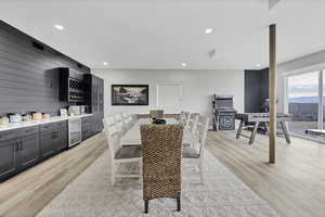 Dining area featuring bar area, beverage cooler, light wood-style flooring, and recessed lighting